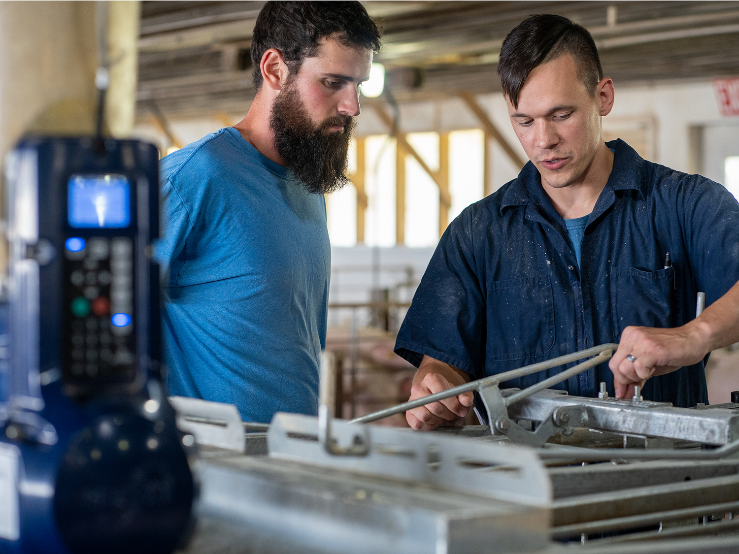 Two workers in a pig barn with blurry GESTAL 3G